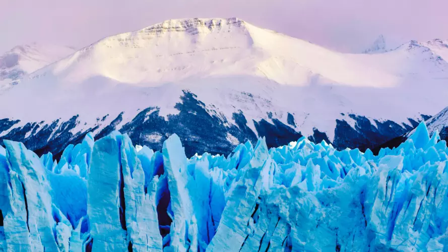 Pink toned glacier in front of a snowy mountain