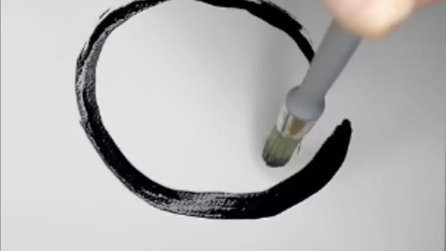 A hand draws an Enso with a paintbrush
